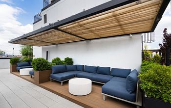 a patio with blue couches and tables and plants